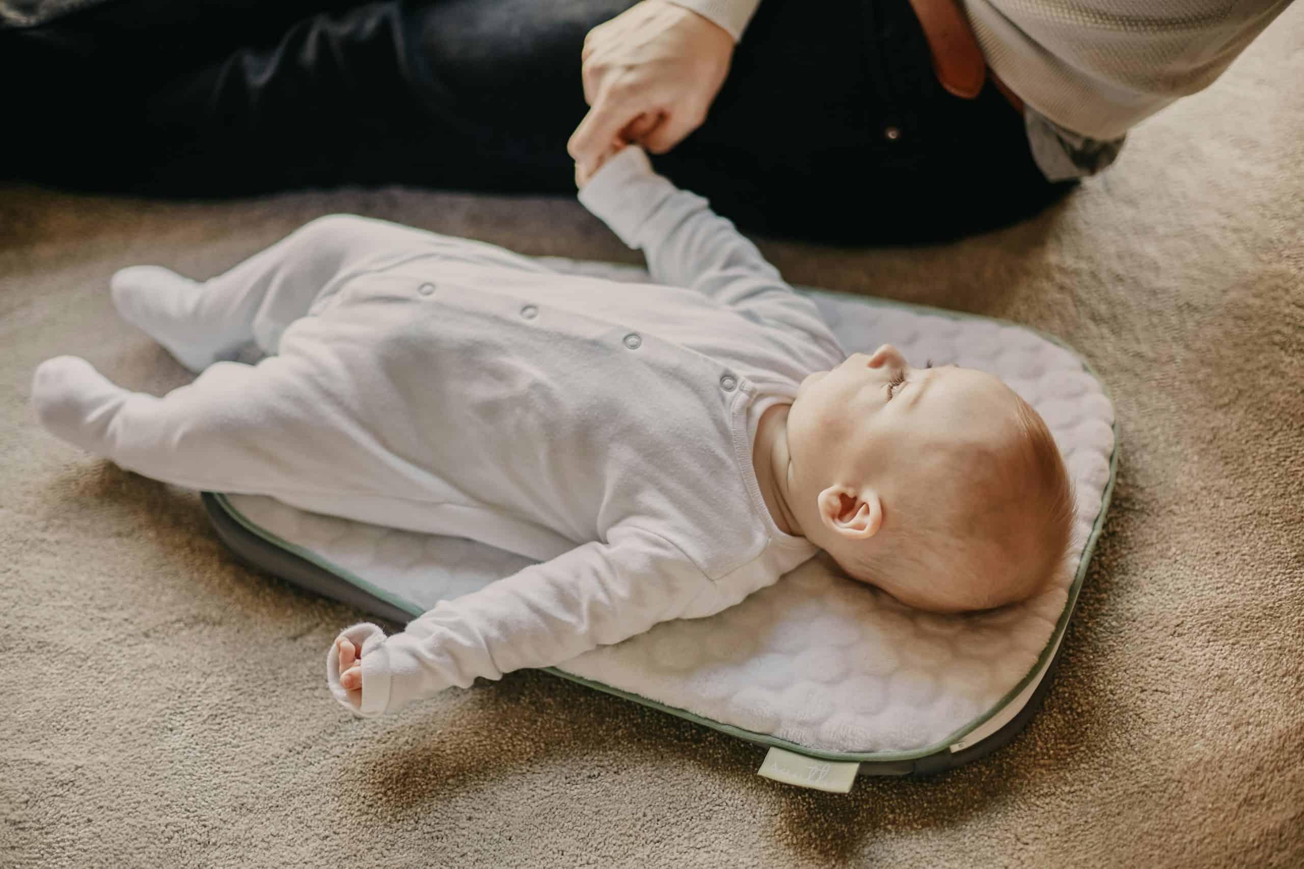 A baby lying on a mat preparing for naptime.