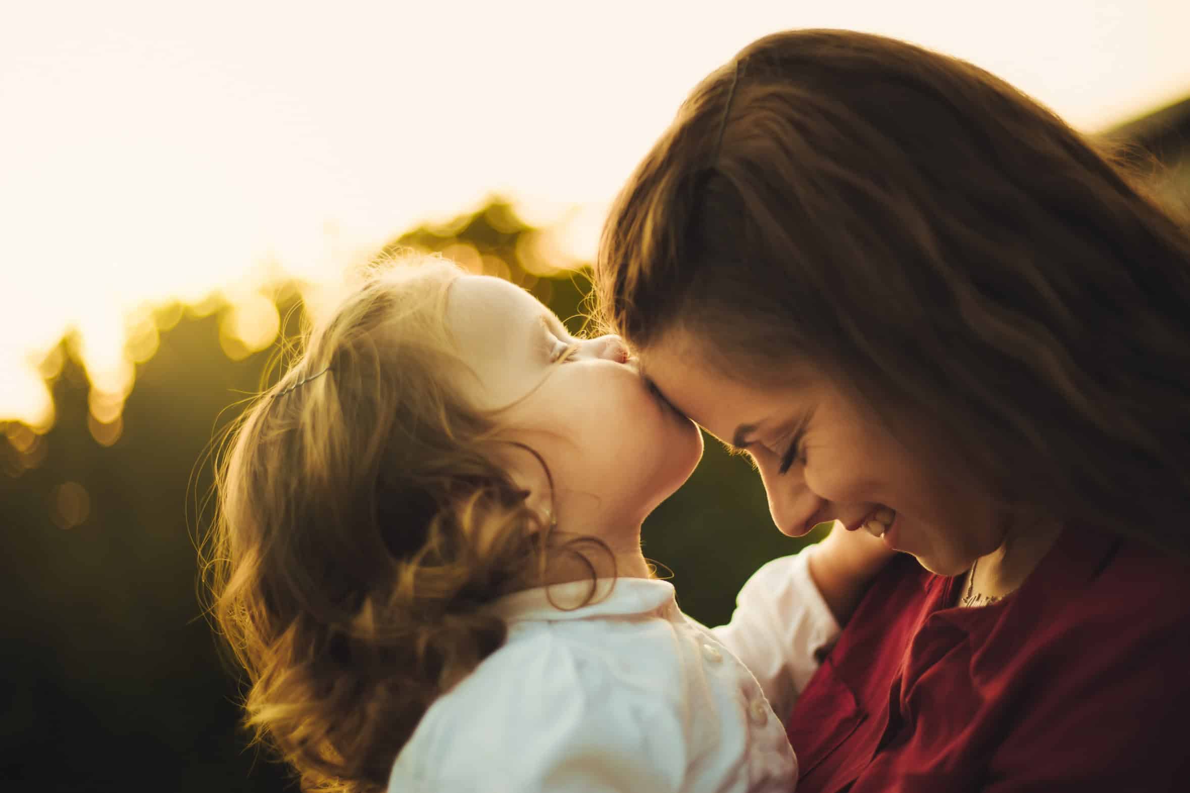 Girl kissing her mom on the forehead