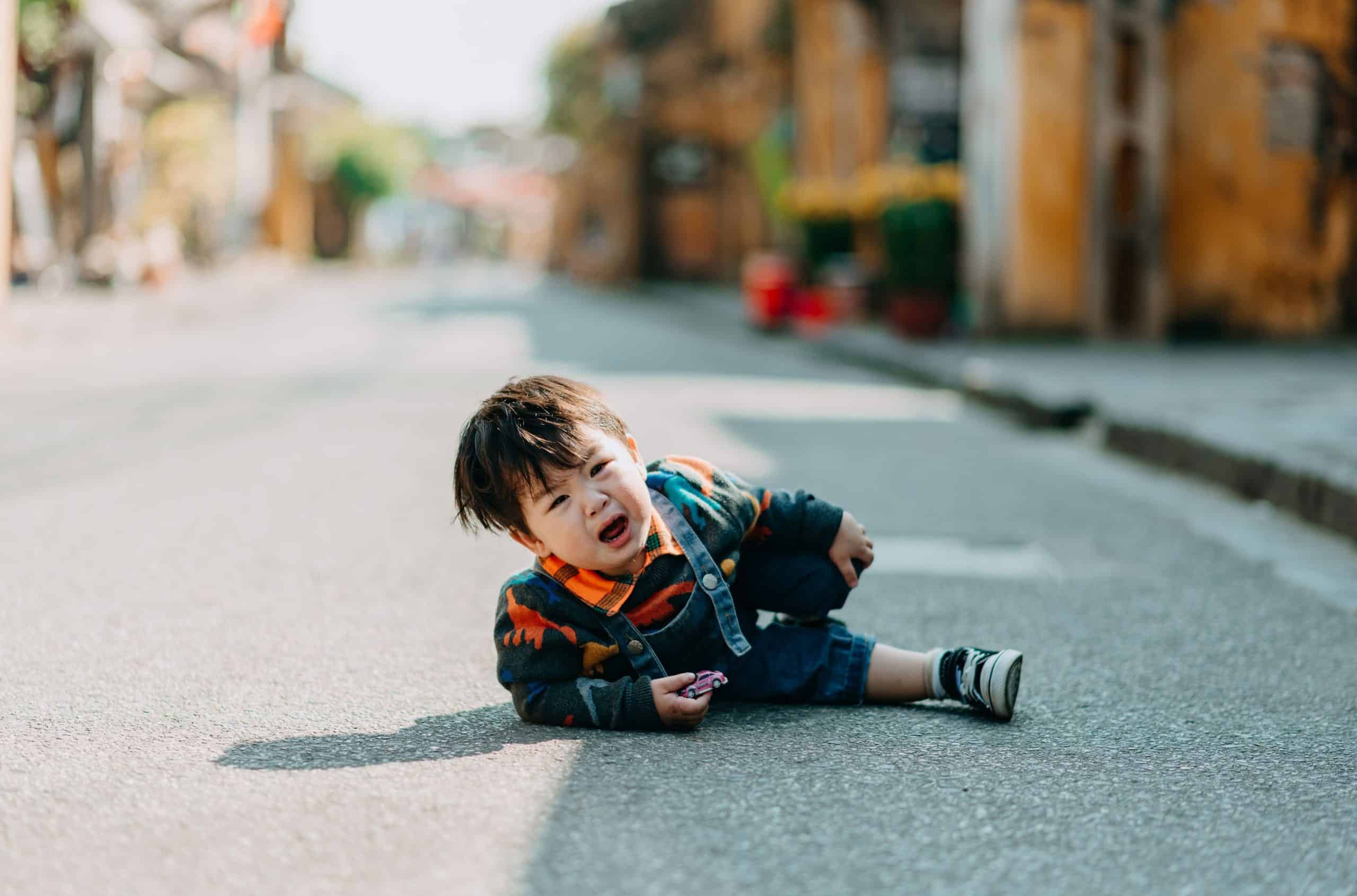 Child in yellow rain jacket riding a tricycle